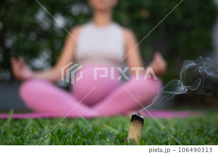young beautiful pregnant woman meditates sitting on a yoga mat on a green lawn. relaxation and healthy lifestyle concept 106490313