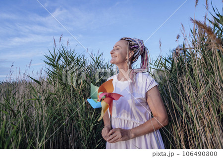 girl with multicolored pigtails, face sideways, holding windmill in her hands in summer outdoors, wind energy girl with multicolored pigtails, face sideways, holding windmill in her hands in summer outdoors, wind energy 106490800
