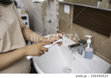 Cleaning of the teeth dentures in the sink with the running water and the toothbrush 106490824