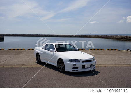 海を背景にした90年代スポーツカー、白のR34GT-R 106491113