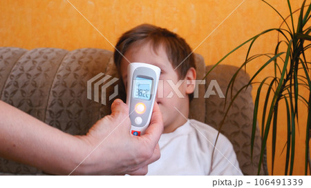A woman's hand with an electronic thermometer measures the temperature of a child 106491339