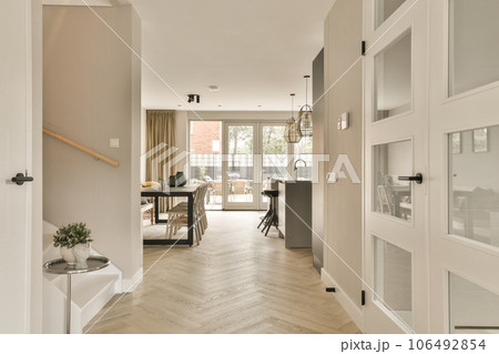 a hallway in a house with wood flooring and white trim on the walls there is an open door leading to another room 106492854