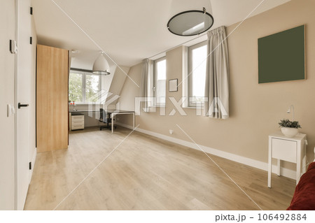 a living room with wood flooring and white trim on the walls, there is a red couch in front 106492884