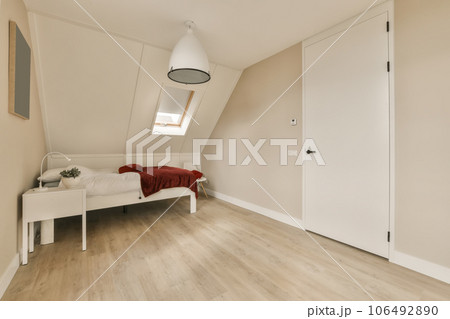 a bedroom with white walls and wood flooring in an attic style home, showing the light colored paint on the walls a bedroom with white walls and wood flooring in an attic style home, showing the light colored paint on the walls 106492890