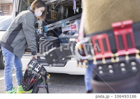 現場で腰道具の準備をする若い女性作業員と男性作業員 106493186