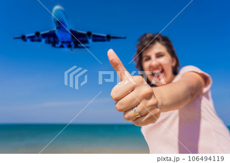 Woman shows a ring with an airplane have fun on the beach watching the landing planes. Traveling on an airplane concept. Text space. Island Phuket in Thailand. Impressive paradise. Hot beach Mai Khao Woman shows a ring with an airplane have fun on the beach watching the landing planes. Traveling on an airplane concept. Text space. Island Phuket in Thailand. Impressive paradise. Hot beach Mai Khao 106494119