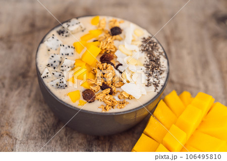 Smoothie bowls made with mango, banana, granola, grated coconut, dragon fruit, chia seeds and mint on wooden background. Concept fruits, vitamins 106495810