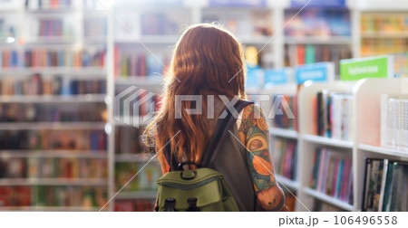 Back view of woman with tattoo wearing backpack shopping in bookstore. Student searching textbook. Concept of education Back view of woman with tattoo wearing backpack shopping in bookstore. Student searching textbook. Concept of education 106496558