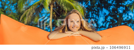 Summer lifestyle portrait of pretty girl sitting on the orange inflatable sofa on the beach of tropical island. Relaxing and enjoying life on air bed BANNER, LONG FORMAT Summer lifestyle portrait of pretty girl sitting on the orange inflatable sofa on the beach of tropical island. Relaxing and enjoying life on air bed BANNER, LONG FORMAT 106496911