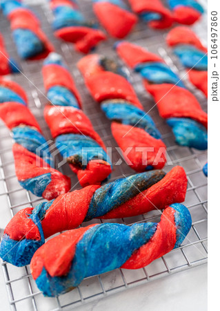 Drizzling white glaze on top of patriotic cinnamon twists. and decorating with star sprinkles. 106497860