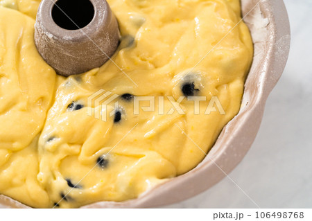 Filling metal bundt cake pan with cake butter to bake lemon blueberry bundt cake. Filling metal bundt cake pan with cake butter to bake lemon blueberry bundt cake. 106498768