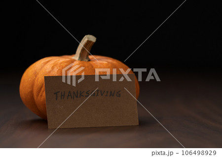 Small orange classic pumpkin on wood table with thanksgiving paper card 106498929