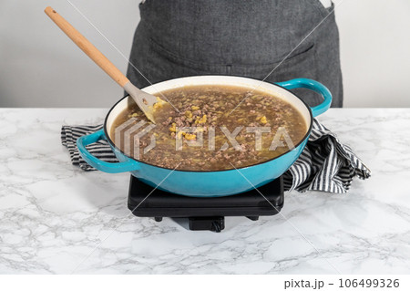 Cooking homemade hamburger helper in enameled cast iron skillet. 106499326