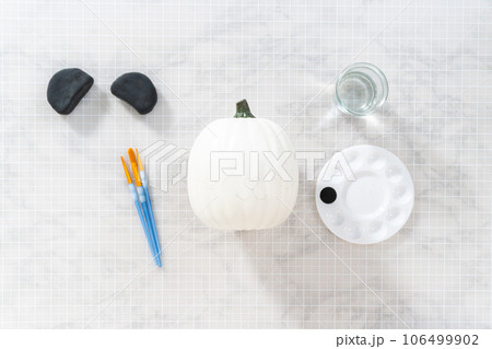 Flat lay. Painting panda face with black acrylic paint to make panda pumpkin for Halloween. Flat lay. Painting panda face with black acrylic paint to make panda pumpkin for Halloween. 106499902