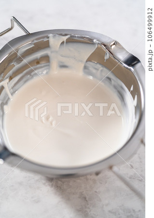 Melted white chocolate chips in a stainless steel double boiler pot. Melted white chocolate chips in a stainless steel double boiler pot. 106499912