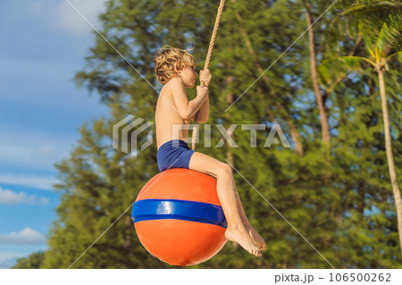 A boy on a swing on the beach. Mom and son spend time on the beach A boy on a swing on the beach. Mom and son spend time on the beach 106500262