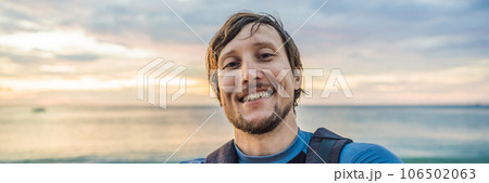 A man takes a selfie on the background of the sea and sunset BANNER, LONG FORMAT 106502063
