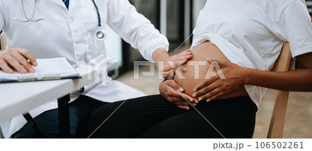 Pregnant african woman has appointment with doctor at clinic. Male gynaecologist OB GYN medic specialist with stethoscope listens to baby's heartbeat in mother's belly. Pregnancy, health care 106502261