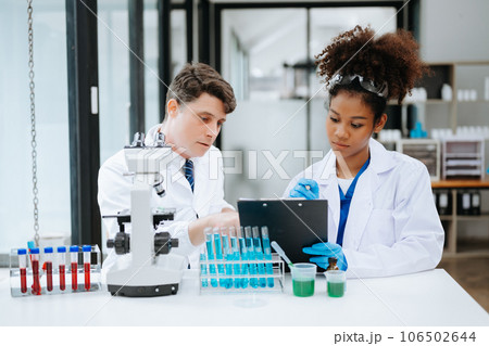 Focused mature male doctor and African female nurse look at tablet and laptop screen discuss anamnesis together. Concentrated diverse medical professionals Focused mature male doctor and African female nurse look at tablet and laptop screen discuss anamnesis together. Concentrated diverse medical professionals 106502644