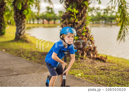 Boy riding scooters, outdoor in the park, summertime. Kids are happy playing outdoors 106503020