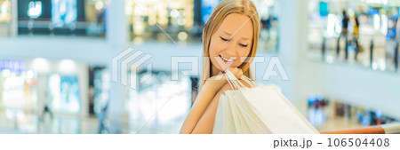 Women carrying a lot of shopping bags in blurred shopping mall BANNER, LONG FORMAT Women carrying a lot of shopping bags in blurred shopping mall BANNER, LONG FORMAT 106504408