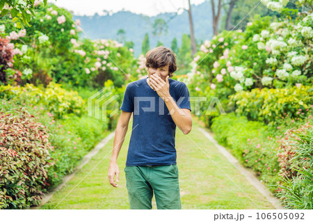 Young man blowing nose in front of blooming tree. Spring allergy concept 106505092