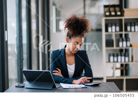 Young beautiful woman typing on tablet and laptop while sitting at the working table office Young beautiful woman typing on tablet and laptop while sitting at the working table office 106505455