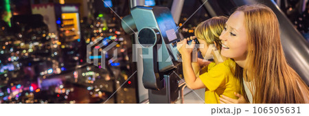 Mom and son are looking at Kuala lumpur cityscape. Use binoculars. Panoramic view of Kuala Lumpur city skyline evening at sunset skyscrapers building in Malaysia. Traveling with kids concept BANNER Mom and son are looking at Kuala lumpur cityscape. Use binoculars. Panoramic view of Kuala Lumpur city skyline evening at sunset skyscrapers building in Malaysia. Traveling with kids concept BANNER 106505631