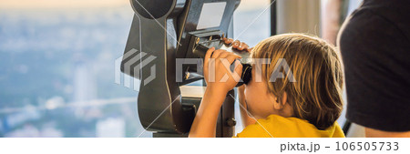 Dad and son are looking at Kuala lumpur cityscape. Use binoculars. Panoramic view of Kuala Lumpur city skyline evening at sunset skyscrapers building in Malaysia. Traveling with kids concept BANNER 106505733