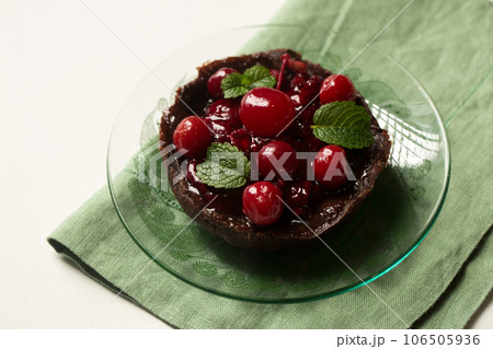 Delicious chocolate dessert with lingonberry jam, cherries and mint on a plate 106505936