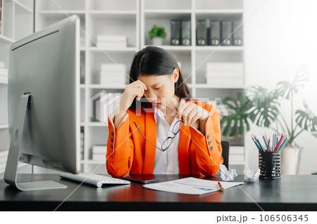 Asian woman feeling migraine head strain.Overworked businesswoman financier while working on laptop and tablet at office. Asian woman feeling migraine head strain.Overworked businesswoman financier while working on laptop and tablet at office. 106506345