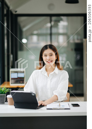 Successful Asian Businesswoman Analyzing Finance on Tablet and Laptop at modern Office Desk tax, report, accounting, statistics, and analytical research concept. 106506393