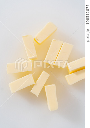 Slicing sticks of unsalted butter on a white cutting board. Slicing sticks of unsalted butter on a white cutting board. 106512875