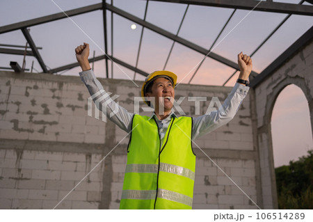 Asian engineer in uniform and helmet at construction site being happy and smiling for success. Successful project and happiness expression after work concept 106514289