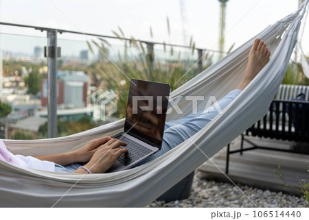 young woman freelancer working in hammock on terrace young woman freelancer working in hammock on terrace 106514440