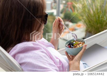 young woman eating chia pudding with nuts and berries 106514442