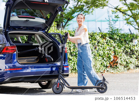 電動キックボードを車に載せようとする女性 106514453