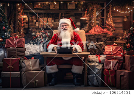 Santa Claus sits in the warehouse of his factory in front of laptop monitor. Santa Claus sits in the warehouse of his factory in front of laptop monitor. 106514551
