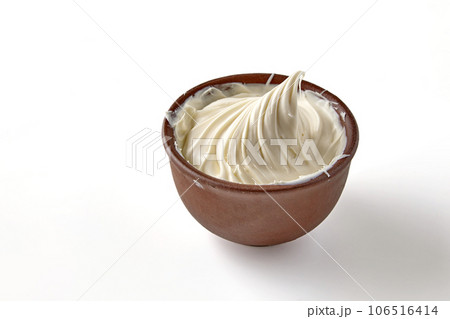 A portion of whipped cream or sour cream twisted into a spiral. Butter in clay bowl isolated on white background A portion of whipped cream or sour cream twisted into a spiral. Butter in clay bowl isolated on white background 106516414