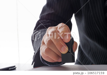 書類に角印を押すビジネスパーソンの手元 書類に角印を押すビジネスパーソンの手元 106517159