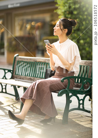 夕暮れの街でベンチに座ってスマホを見る若い女性 夕暮れの街でベンチに座ってスマホを見る若い女性 106518572