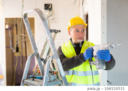 Repair man in uniform working with screw gun Repair man in uniform working with screw gun 106520531