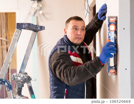 Repair man measuring evenness of wall Repair man measuring evenness of wall 106520669