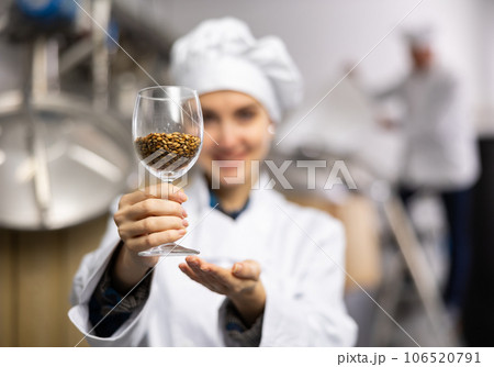 Portrait of positive female brewer with a glass of barley at brewery 106520791