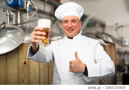 Portrait of brewer who is standing with glass of beer on his workplace in brew-house Portrait of brewer who is standing with glass of beer on his workplace in brew-house 106520905