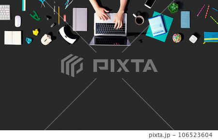 Person using a laptop computer with office supplies 106523604