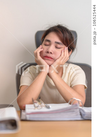 Stressed Asian woman having Tired and Sleepy while working, female businesswoman having headache at office, Exhausted woman with documents folder stack at home late night. Overworked and Overtime Stressed Asian woman having Tired and Sleepy while working, female businesswoman having headache at office, Exhausted woman with documents folder stack at home late night. Overworked and Overtime 106525444