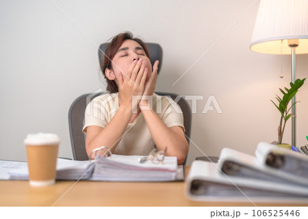 Stressed Asian woman having Tired and Sleepy while working, female businesswoman having headache at office, Exhausted woman with documents folder stack at home late night. Overworked and Overtime 106525446