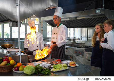 Chef teacher teaches cooking to the group children in class kitchen room Chef teacher teaches cooking to the group children in class kitchen room 106525626