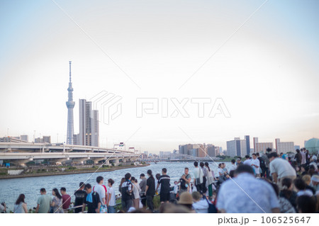 【日本】夕方の汐入公園の土手で隅田川花火大会の開始を待つ群衆とスカイツリーのある風景 【日本】夕方の汐入公園の土手で隅田川花火大会の開始を待つ群衆とスカイツリーのある風景 106525647